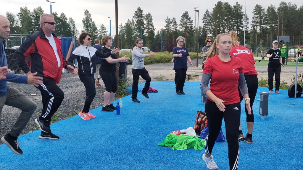 Joukko työntekijöitä lämmittelee liikuntaa varten.